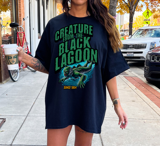 A black oversized shirt featuring a vintage-style graphic of the Creature from the Black Lagoon, capturing the eerie and classic horror vibe.